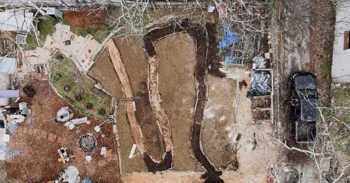 Aerial shot of a backyard construction site with various materials and earthworks.